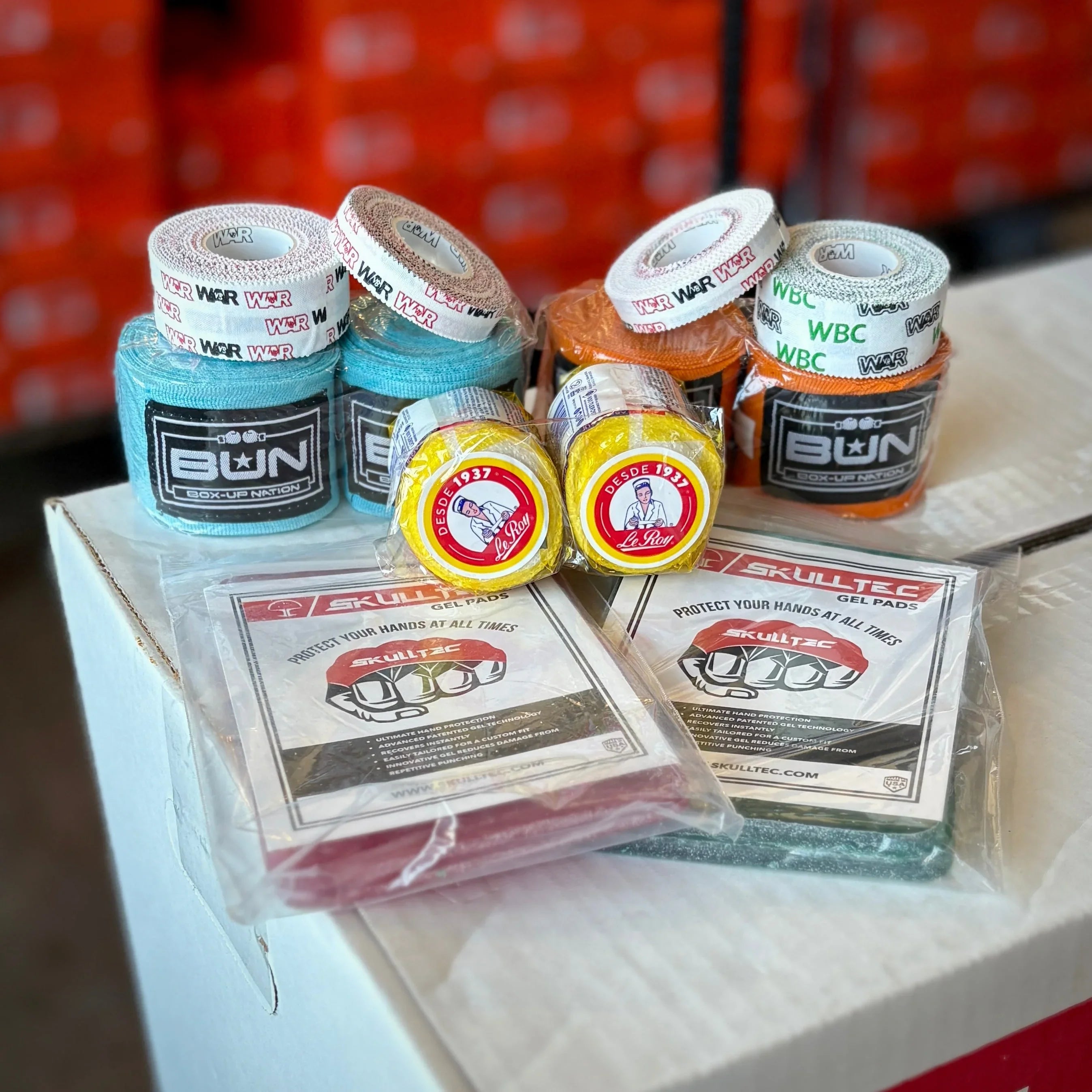 Assorted boxing hand wraps and gel pads on display box, pro boxing equipment selection.