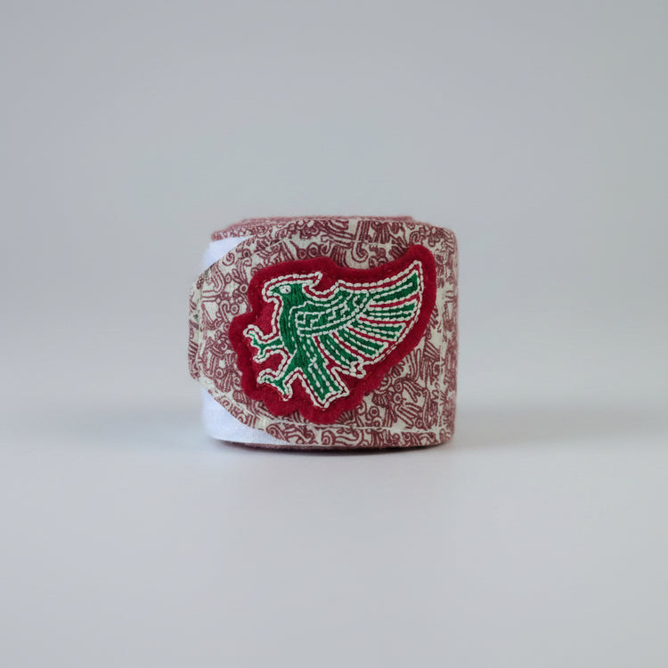 A small embroidered patch featuring a stylized eagle in green and white thread. Box-up nation heritage handwraps. 