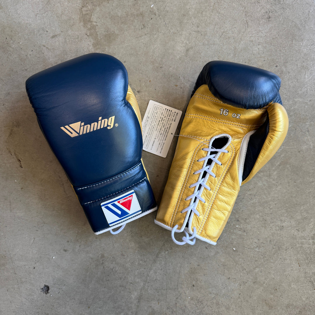 Blue and yellow boxing gloves on a concrete floor with a visible brand logo.