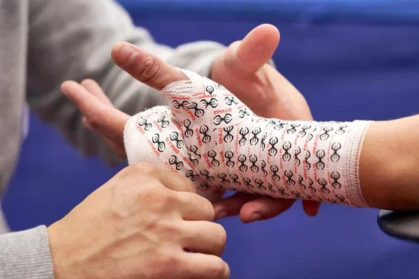 Trainer wrapping a boxer's hand with patterned boxing gauze before training