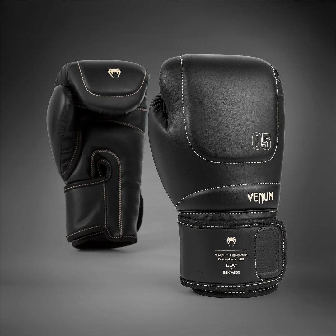 Black Venum boxing gloves with white stitching and logo, pro-grade training gear