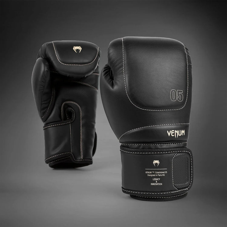 Black Venum boxing gloves with white stitching and logo, pro-grade training gear